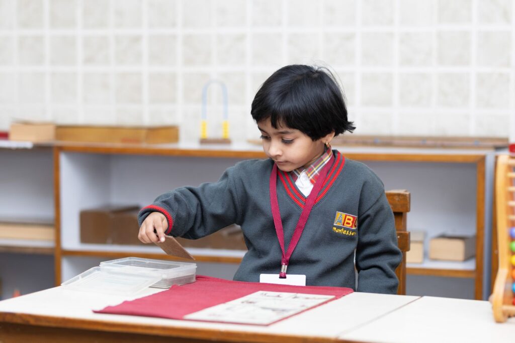 Montessori sınıfında öğrenme materyaliyle çalışan çocuk
